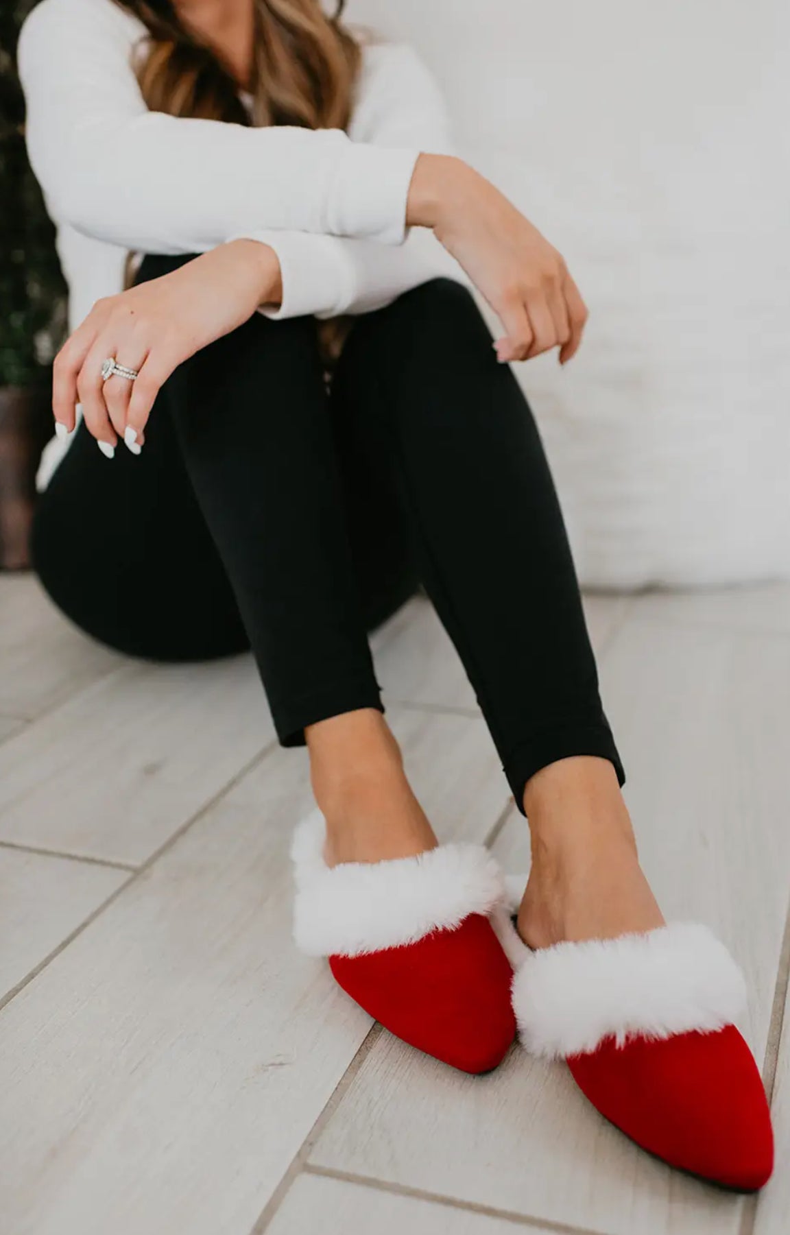 women sitting on ground wearing red and white Santa Slippers